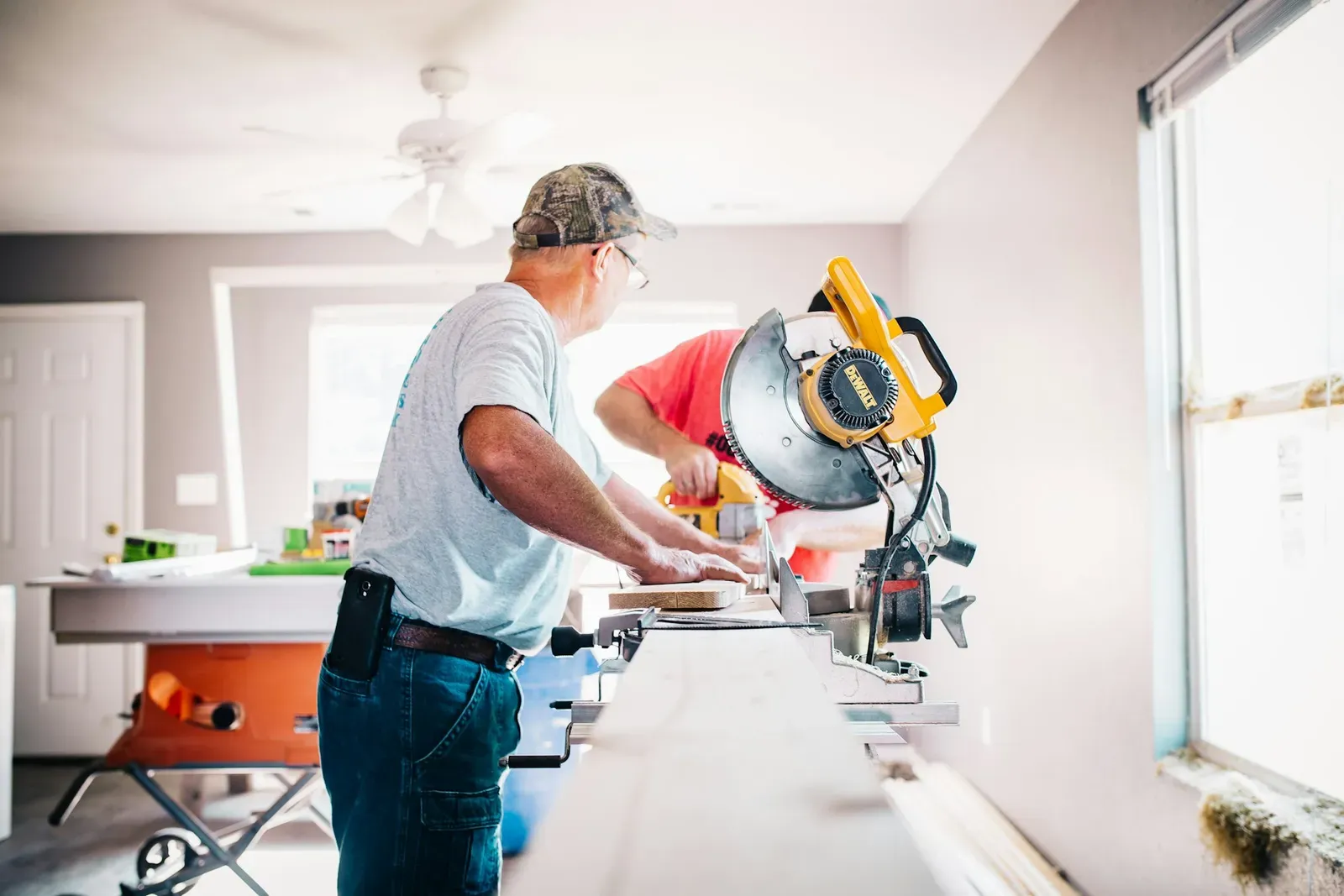 Remodeling crew cutting trim on a miter saw inside a house